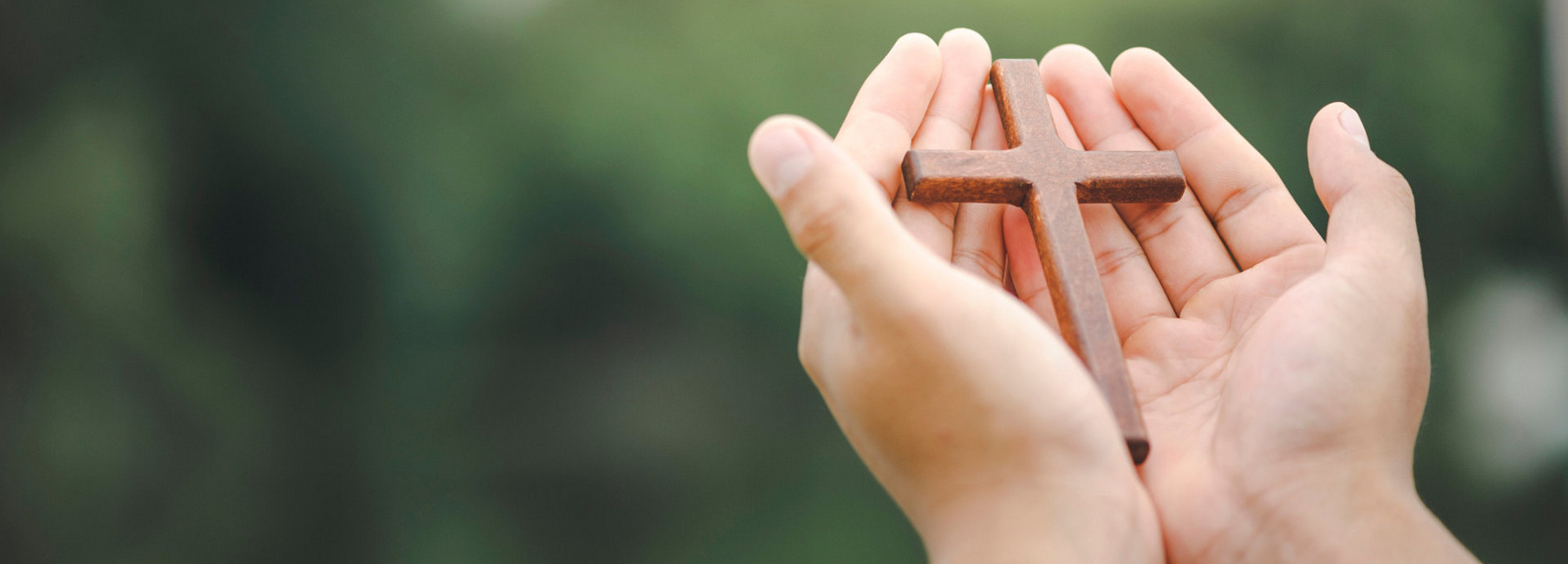 Hände halten ein Holzkreuz