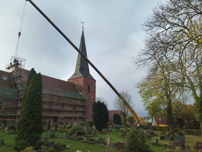 Mit einem Kran wurde der neu gefertigte Sandstein freischwebend weit über den Friedhof bis an die richtige Stelle zu befördert.