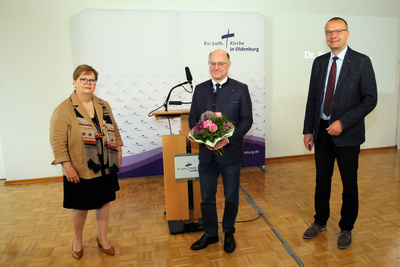 Nach zehnjähriger Amtszeit war Oberkirchenrat Detlef Mucks-Büker (Mitte) im Mai 2021 von den Synodalen der oldenburgischen Kirche im Amt bestätigt worden. Gratulation von Synodenpräsidentin Sabine Blütchen (links) und Bischof Thomas Adomeit (rechts).