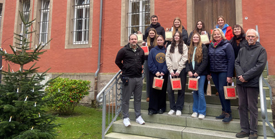 Schülerinnen und Schüler bringen zusammen mit den Lehrerinnen und Lehrern die weihnachtlichen Geschenke in die Justizvollzugsanstalt für Frauen und werden dort von den Mitarbeitenden empfangen.