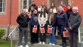 Schülerinnen und Schüler bringen zusammen mit den Lehrerinnen und Lehrern die weihnachtlichen Geschenke in die Justizvollzugsanstalt für Frauen und werden dort von den Mitarbeitenden empfangen.