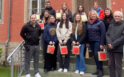 Schülerinnen und Schüler bringen zusammen mit den Lehrerinnen und Lehrern die weihnachtlichen Geschenke in die Justizvollzugsanstalt für Frauen und werden dort von den Mitarbeitenden empfangen.