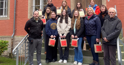 Schülerinnen und Schüler bringen zusammen mit den Lehrerinnen und Lehrern die weihnachtlichen Geschenke in die Justizvollzugsanstalt für Frauen und werden dort von den Mitarbeitenden empfangen.