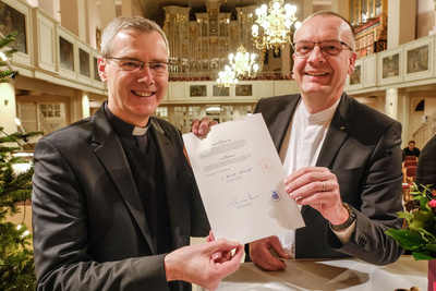 Heiner Wilmer, Bischof im Bistum Hildesheim (links), und Bischof Thomas Adomeit, Ratsvorsitzender der Konföderation evangelischer Kirchen in Niedersachsen (rechts), mit der Vereinbarung „Christliche Religion nach evangelischen und katholischen Grundsätzen“.